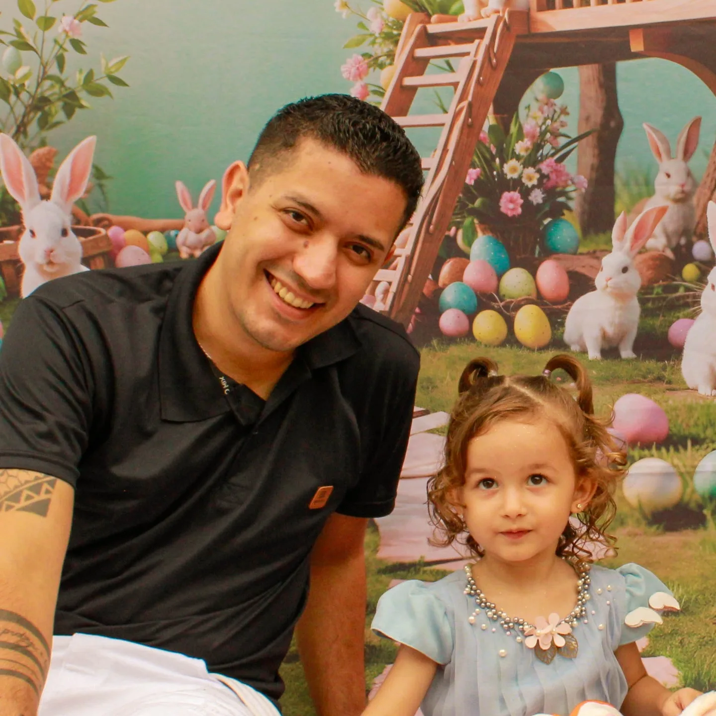 Homem e menina posam diante de uma decoração de festa com coelhos.